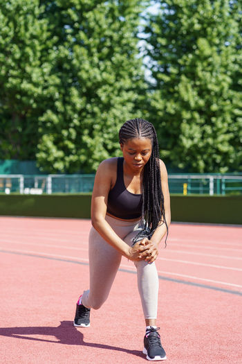 Persistent black woman with long braids tries hard to pump gluteal muscles taking care of fit body