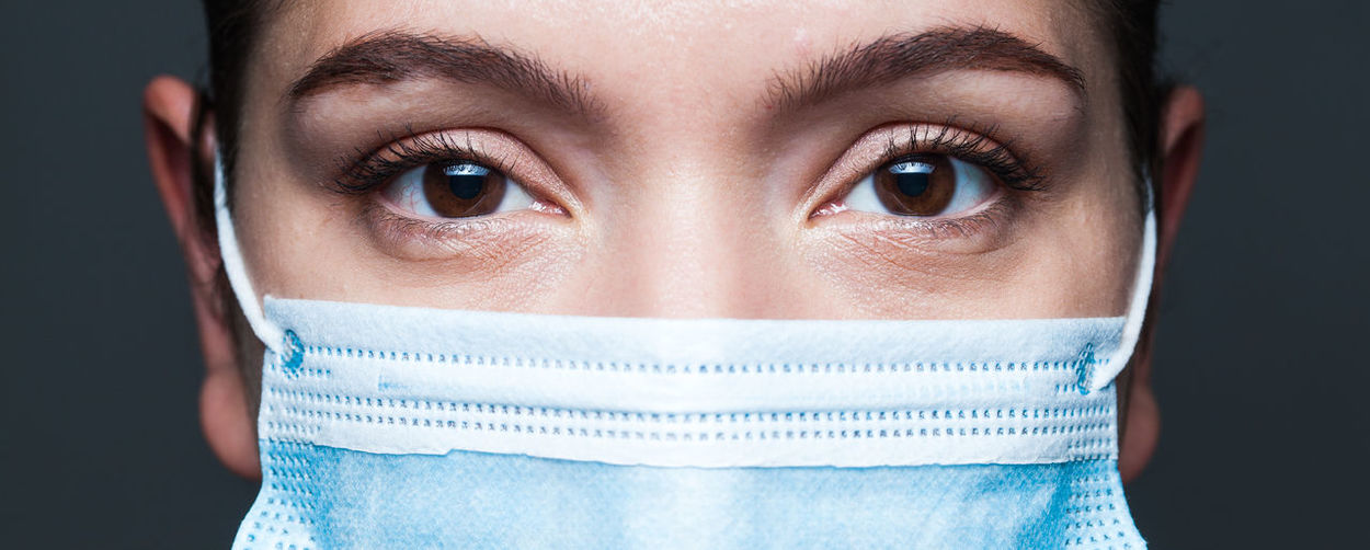 Close-up portrait of woman wearing mask against black background