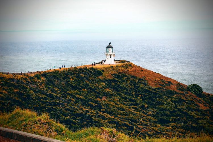 Lighthouse on cliff against sea