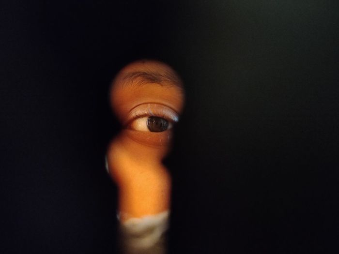Close-up of human eye seen through key hole