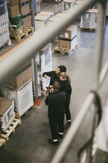 Female and male colleagues examining packages while standing in logistics warehouse
