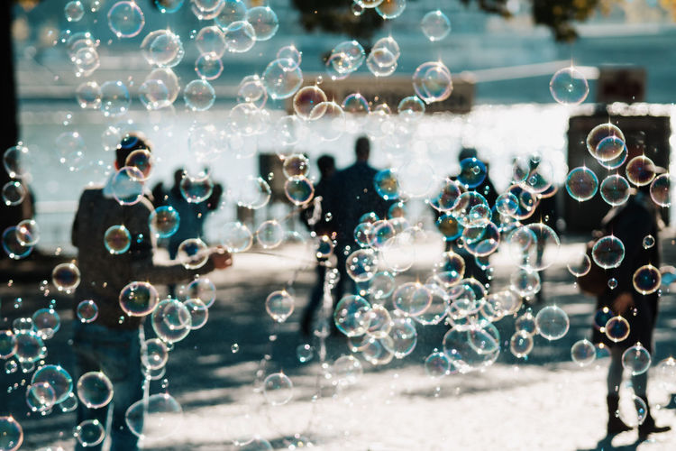 Bubbles and people on footpath during sunny day