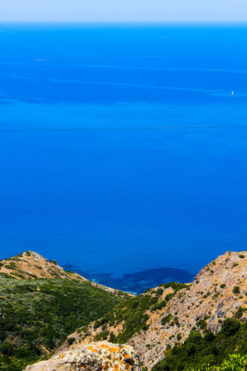 High angle view of sea and mountains against blue sky