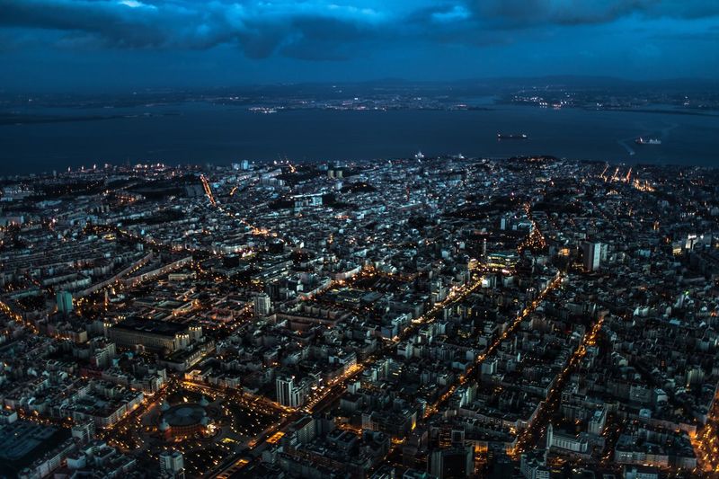 Aerial view of illuminated cityscape of lisbon portugal against sky