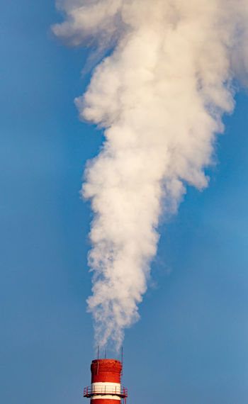 Low angle view of smoke stacks against blue sky