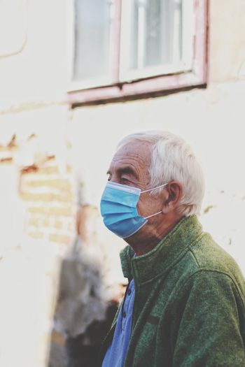 Close-up of senior man wearing flu mask standing outdoors