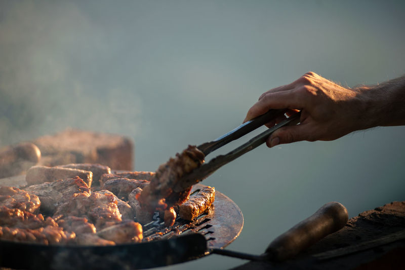 Cropped hand of man preparing food on barbecue