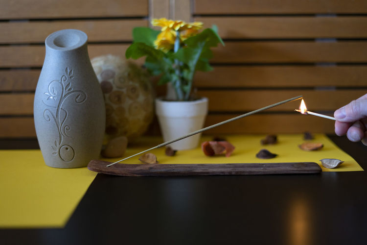 Hand lighting an incense stick with a match.